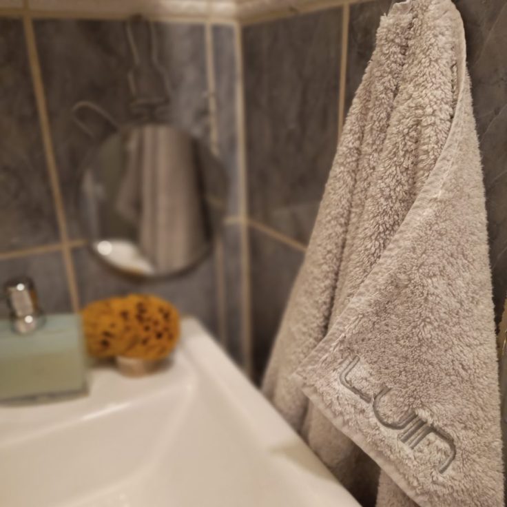 LuinLiving merkkinen käsipyyhe roikkuu kylpyhuoneessa lavuaarin vieressä.
